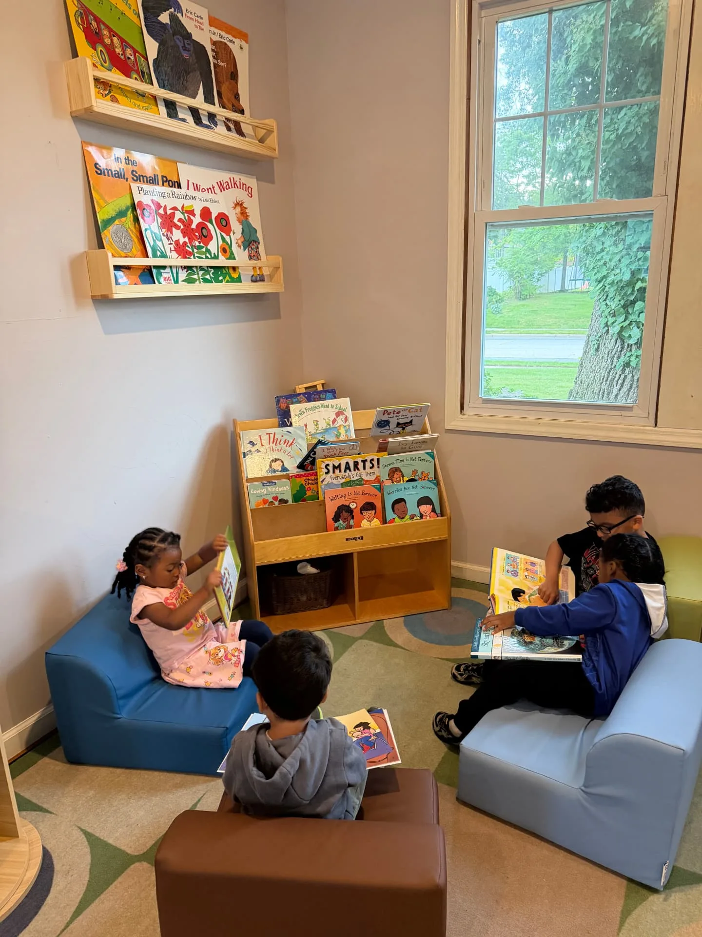 Children reading picture books in the cozy classroom reading corner