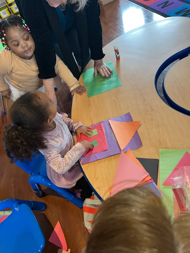 Teacher helping children create a colorful paper craft