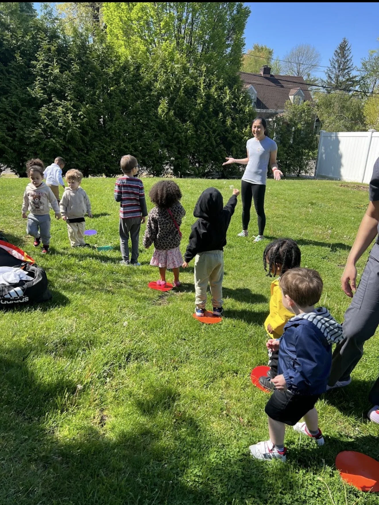 Children playing an outdoor movement game on the grass with their teacher